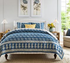 a blue and white bed with two pictures above it