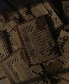 many old books tied together with string and twine on the floor in front of a dark background