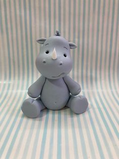 a small toy hippo sitting on top of a blue and white stripped sheeted surface