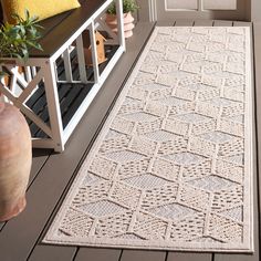 a white rug sitting on top of a wooden floor next to a potted plant