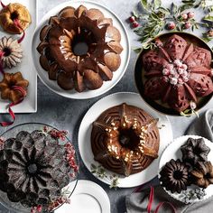 a table topped with cakes and bundt cakes covered in frosting next to other desserts