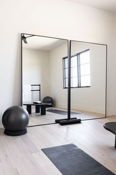 an exercise room with mirrors and yoga balls on the floor, in front of a white wall