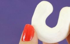 a woman's hand with red and white nail polish holding a fake toothbrush