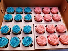 a box filled with blue and pink cupcakes