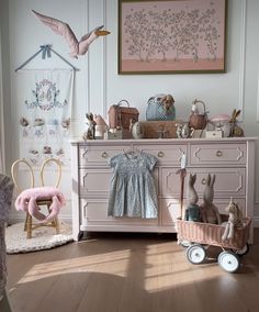 a baby's room is decorated in pink and white with toys on the dresser