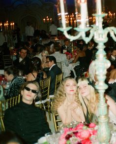 a group of people sitting at tables with candles in the background