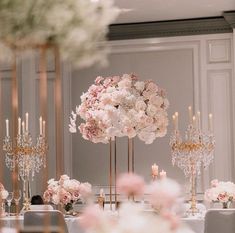 a table with flowers and candles on it in a room filled with white tables cloths