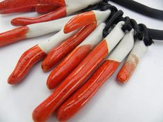 an orange and white necklace with black cord on it's end, sitting on a table