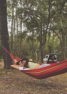 a woman laying in a hammock next to a tree