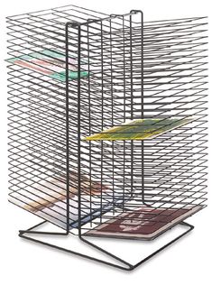 a bird is sitting on top of a wire cage that holds several magazines and papers