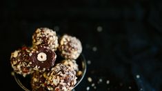 a bowl filled with chocolate covered candies on top of a black table next to nuts and sprinkles