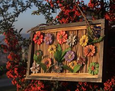 a wooden box with flowers on it hanging from a tree