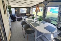 the interior of a recreational vehicle with dining table and couches in front of large windows