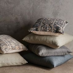 four pillows stacked on top of each other in front of a concrete wall and floor