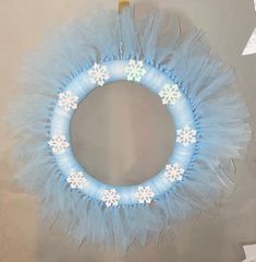 a blue wreath with snowflakes hanging from it's side on a wall