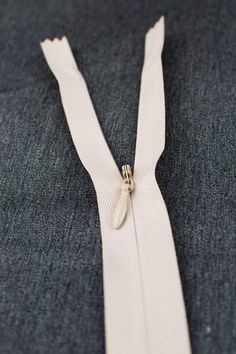 a close up of a white zipper on a blue jacket with a silver clasp around it