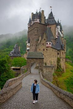 a woman standing on a bridge in front of a castle