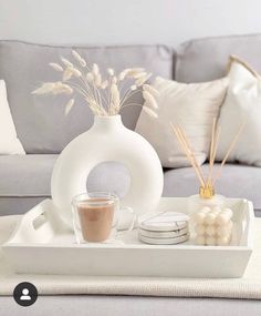 a tray with candles, coffee cup and marshmallows on it in front of a gray couch