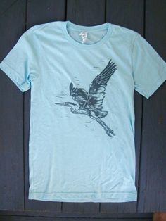 a blue t - shirt with a bird drawn on it