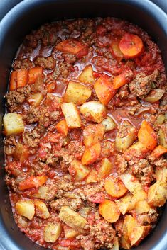 a crock pot filled with meat, potatoes and carrots