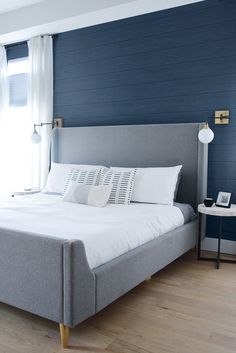 a bedroom with blue walls and white bedding