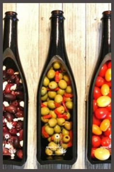 three wine bottles filled with different types of olives, tomatoes and other foods in them