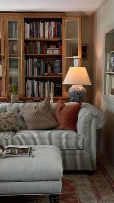 a living room filled with furniture and bookshelves next to a lamp on a table