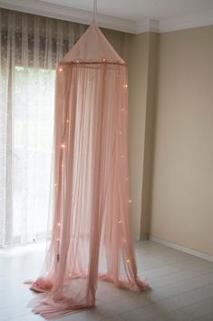 a canopy bed with lights hanging from it's sides in a room next to a window