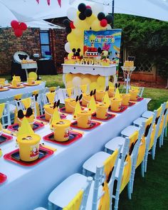 a mickey mouse themed birthday party with yellow and red tablecloths, white chairs, and balloons