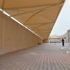 a man is standing under an awning in the middle of a walkway with bricks on both sides