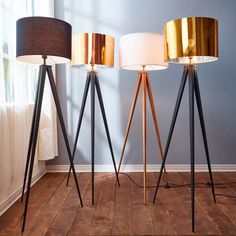 three floor lamps on wooden floors in front of a window