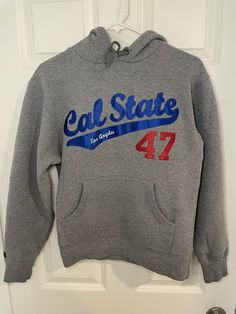 Cal State Los Angeles CSLA LA Sz XS Extra Small Gray Hoodie Embroidered Sweater. The logo is in the style of the LA Dodgers. Very cool piece. On a JanSport tag. PLEASE NOTE: The embroidery does have a FLAW, it is missing a piece of string about 1 inch long under the Cal. So the patch is not flush to the sweater. See photos for details. Please also note that this is a VERY SMALL sweater, please check the measurements before purchasing. Measurements are approximate while laying flat. Armpit to arm Gray Long Sleeve Varsity Hoodie, Gray Hoodie With Embroidered Logo For Fall, Gray Varsity Hoodie Sweatshirt, Gray Embroidered Logo Hoodie For Fall, Gray Fall Hoodie With Embroidered Logo, Gray Varsity Hoodie For Streetwear, Sporty Winter Hoodie With Embroidered Logo, Winter Sporty Hoodie With Embroidered Logo, Casual Hooded Hoodie With Letter Embroidery