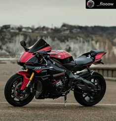 a red and black motorcycle parked on top of a parking lot next to a mountain