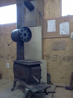 an old stove sitting inside of a room with wood on the floor and walls around it