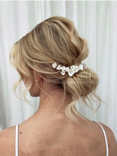 a woman with blonde hair wearing a white flower clip in her left hand and the back of her head