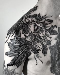 the back of a man's shoulder with flowers and leaves on it