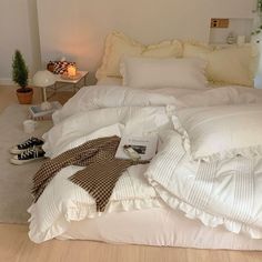 an unmade bed with white sheets and pillows on the floor next to a lamp