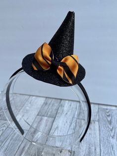 This little witch hat fascinator is perfect for Halloween or any day of the year! Hat is attached to a plastic headband covered with black silky material. Headband is soft and flexible, which makes for a comfortable fit. It is a standard size headband, which will fit both adults and older children. Witch hat is made of glitter foam and is attached to the headband, but is able to slide on the headband so you can wear the hat on the top of your head or on either side. Hat is adorned with a gold an Gold Costume Hats And Headpieces For Halloween, Halloween Costume Hat Accessories, Halloween Cat Ears Hair Accessories For Costume Party, Spooky Black Costume Hats And Headpieces For Party, Halloween Costume Party Cat Ears Hair Accessories, Spooky Black Costume Hat, Adjustable Cat Ears Costume Hat For Halloween, Halloween Cat Ears Costume Accessories, Adjustable Cat Ears Headpiece For Halloween