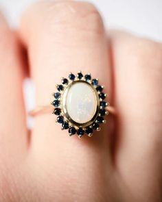 a woman's hand holding a ring with a white and black stone in it