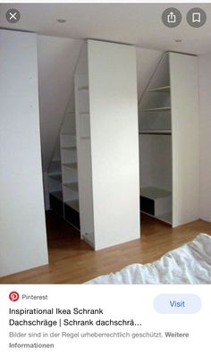 an empty room with white walls and open shelving units in the corner, next to a bed