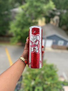 a person holding up a red and white can with an elephant drawn on it's side