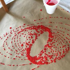 a paper bag with red paint splattered on it next to a white cup