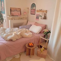 an unmade bed sitting next to a window in a room with white curtains and pink bedspread