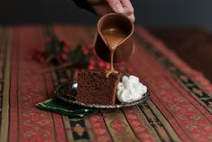 someone pouring caramel sauce on a piece of cake