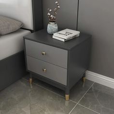 a nightstand with a book on it next to a bed and a plant in a vase