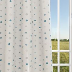 an open window with a white curtain and blue polka dot print on it, in front of a grassy field