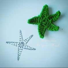 a green crocheted star ornament sitting on top of a white surface