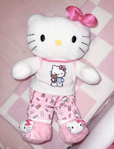 a hello kitty stuffed animal laying on top of a pink and white checkered blanket