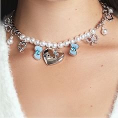 a close up of a woman wearing a necklace with charms on it and a heart