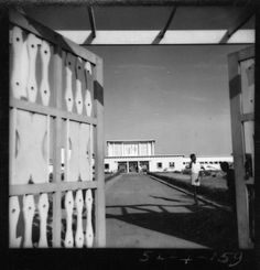 black and white photograph of an open door to a building with scissors on the outside